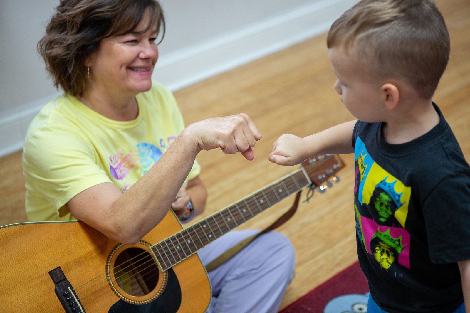 Kids MusicRound class with children gathered around a teacher and guitar